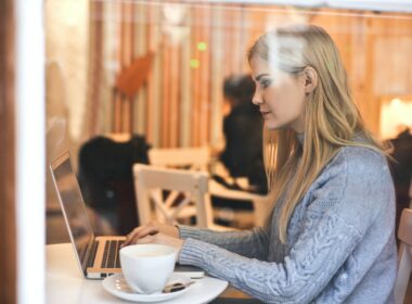 Young blonde woman using computer in a coffee shop.