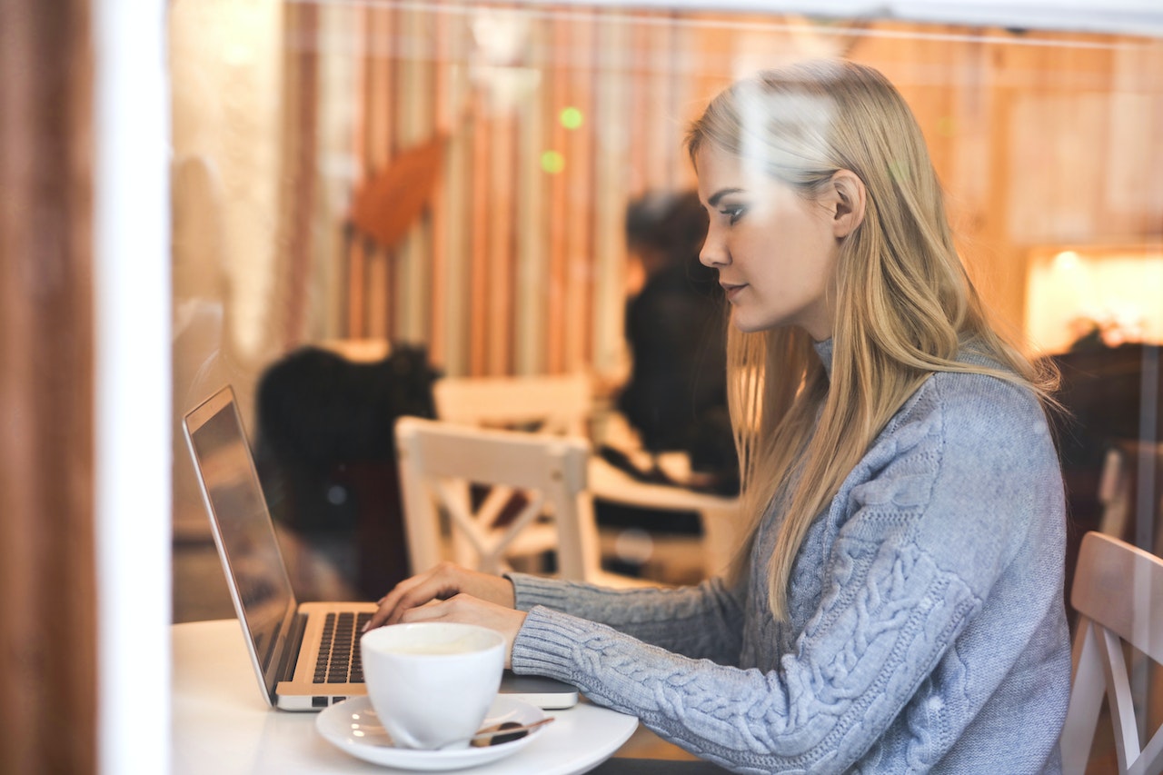 Young blonde woman using computer in a coffee shop.