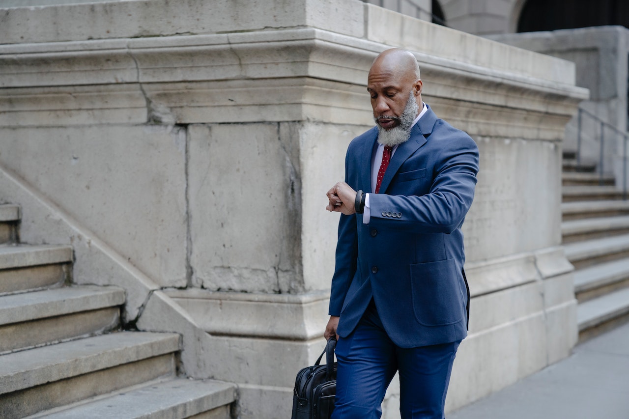 Serious black man in formal suit checking his watch.