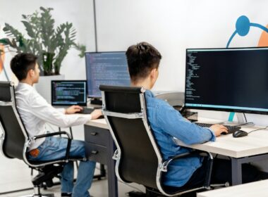 Two men working on code on their computers.
