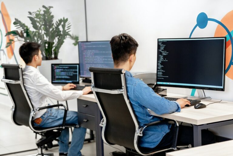 Two men working on code on their computers.