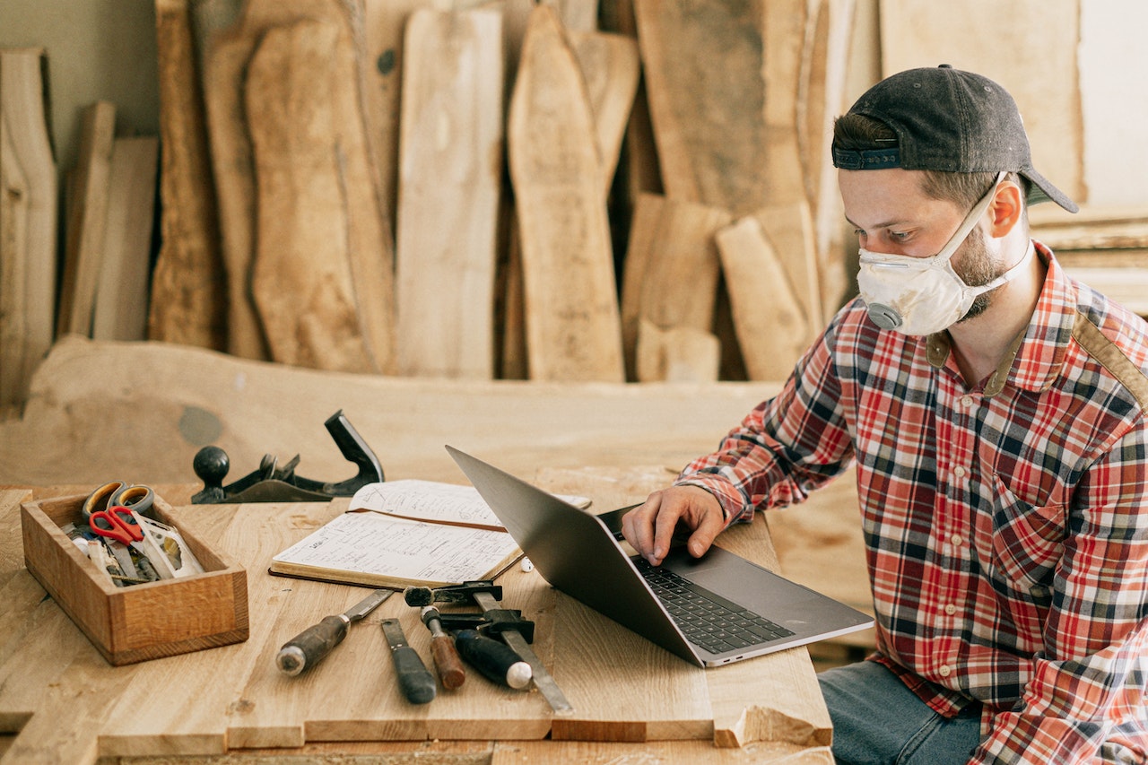Man using computer in woodworking shed.