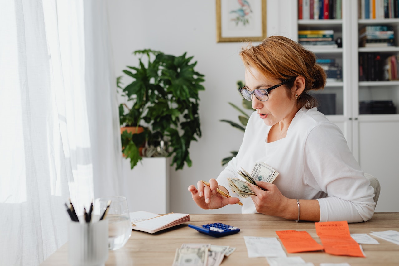 Woman sitting at desk counting money.