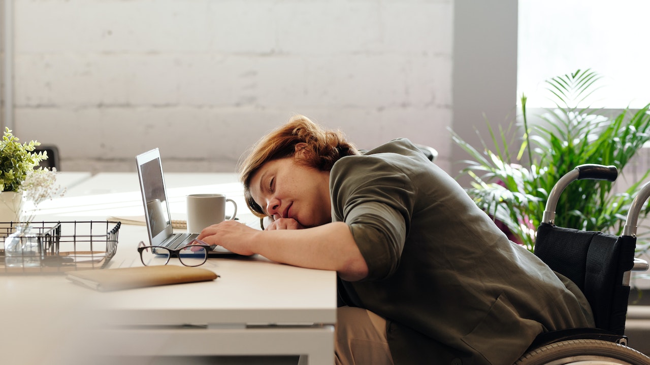Woman sleeping at her desk on her computer.