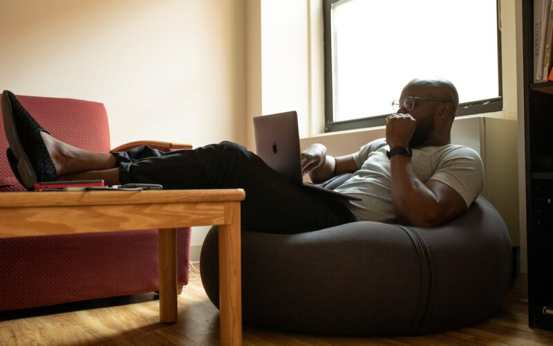 Black man working from home sitting on a beanbag.