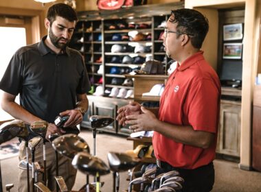 Salesman helping man buy golfclubs at sporting goods store