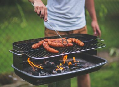 Man grilling hot dogs over charcoal