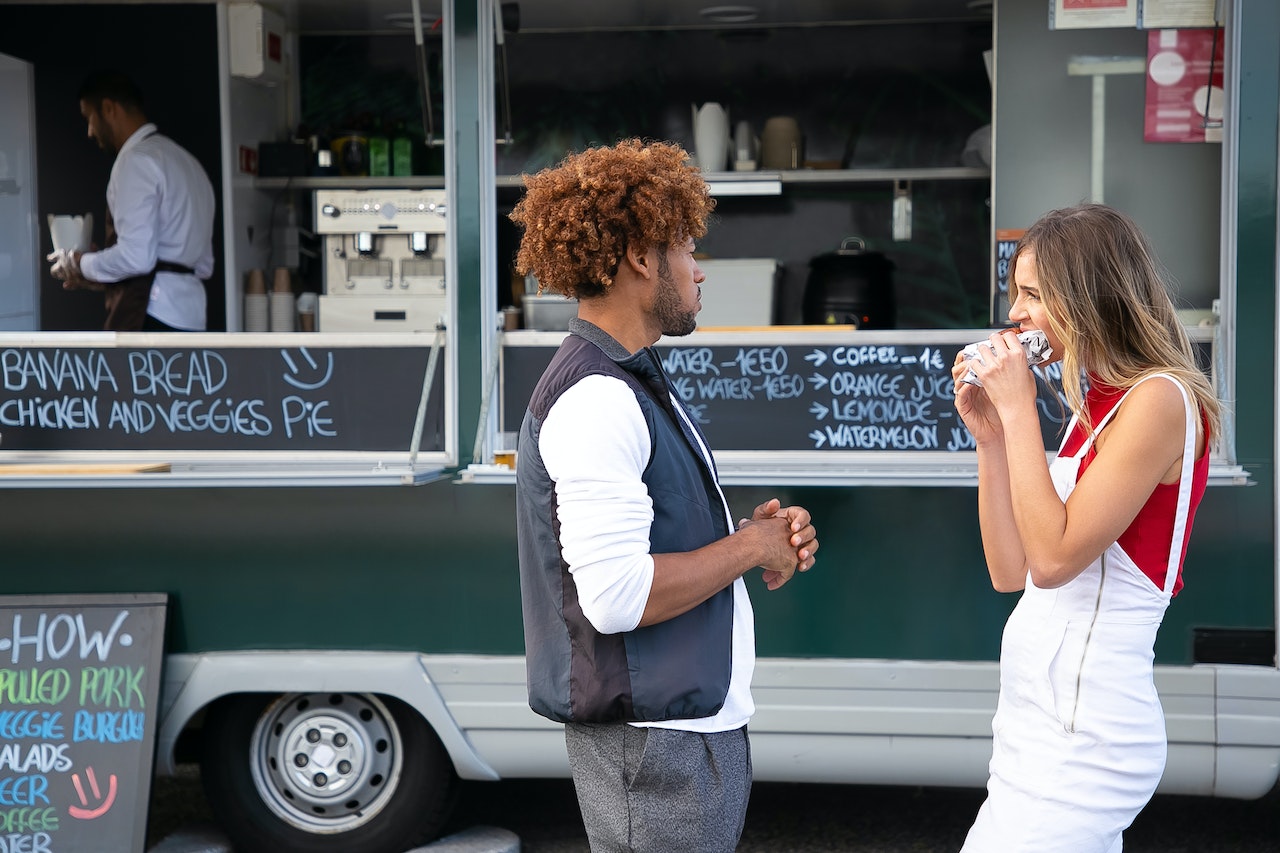 Man and woman eating at a food truck.