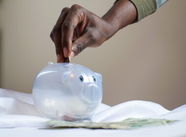 Person's handing putting money into a piggy bank