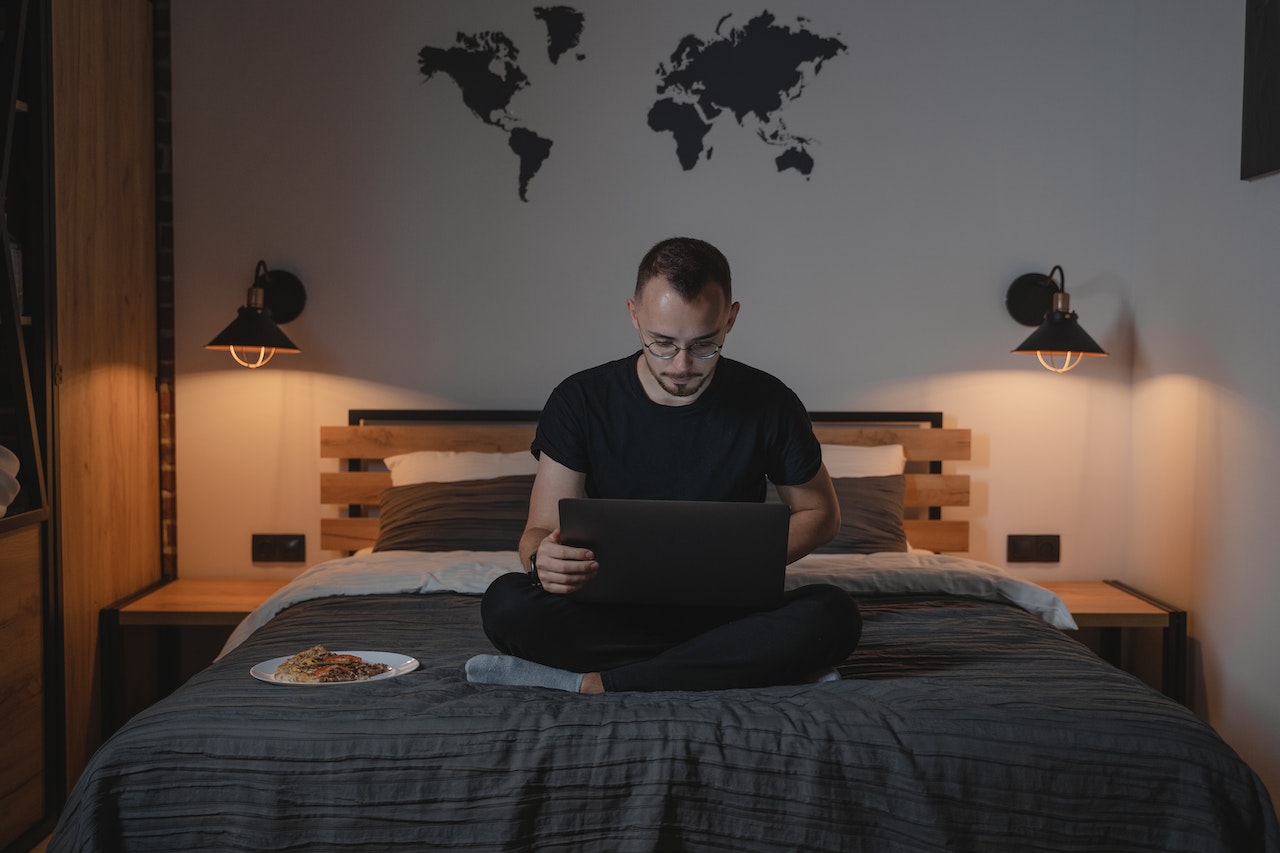 Man using laptop while sitting on bed