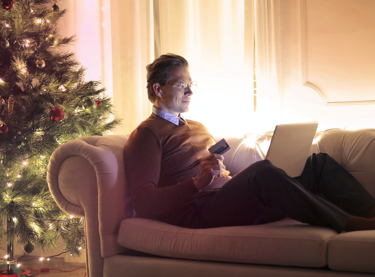 Man doing online shopping next to his Christmas tree