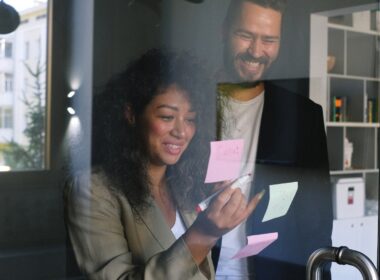 Man and woman smiling, working on sticky notes in office