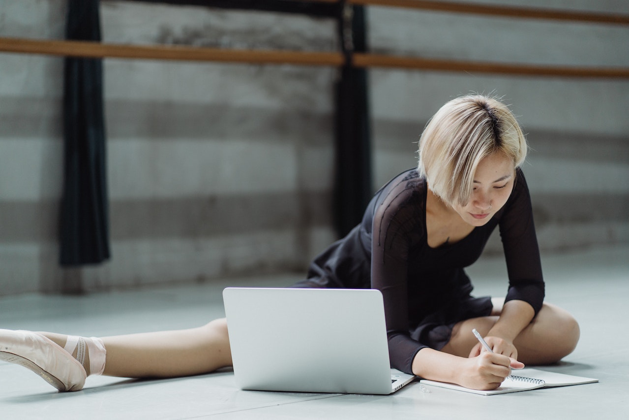 Woman ballerina stretching and working on computer