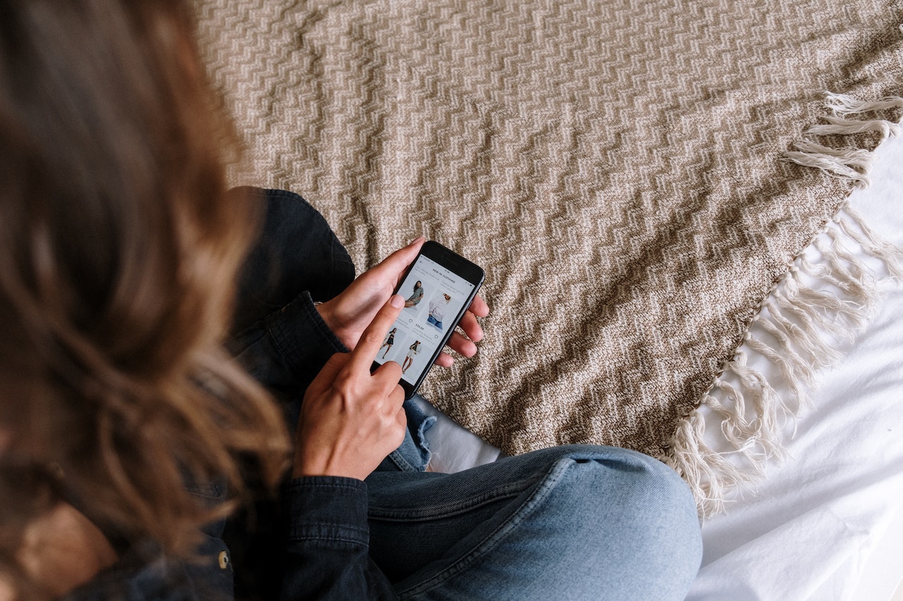 Woman in blue jeans online shopping on her phone