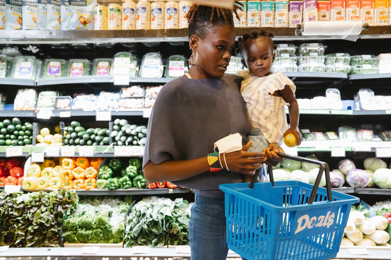 Mother carrying daughter while shopping at grocery store