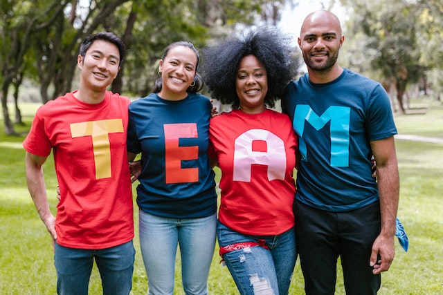 Group of diverse people wearing t-shirts that spell "TEAM"