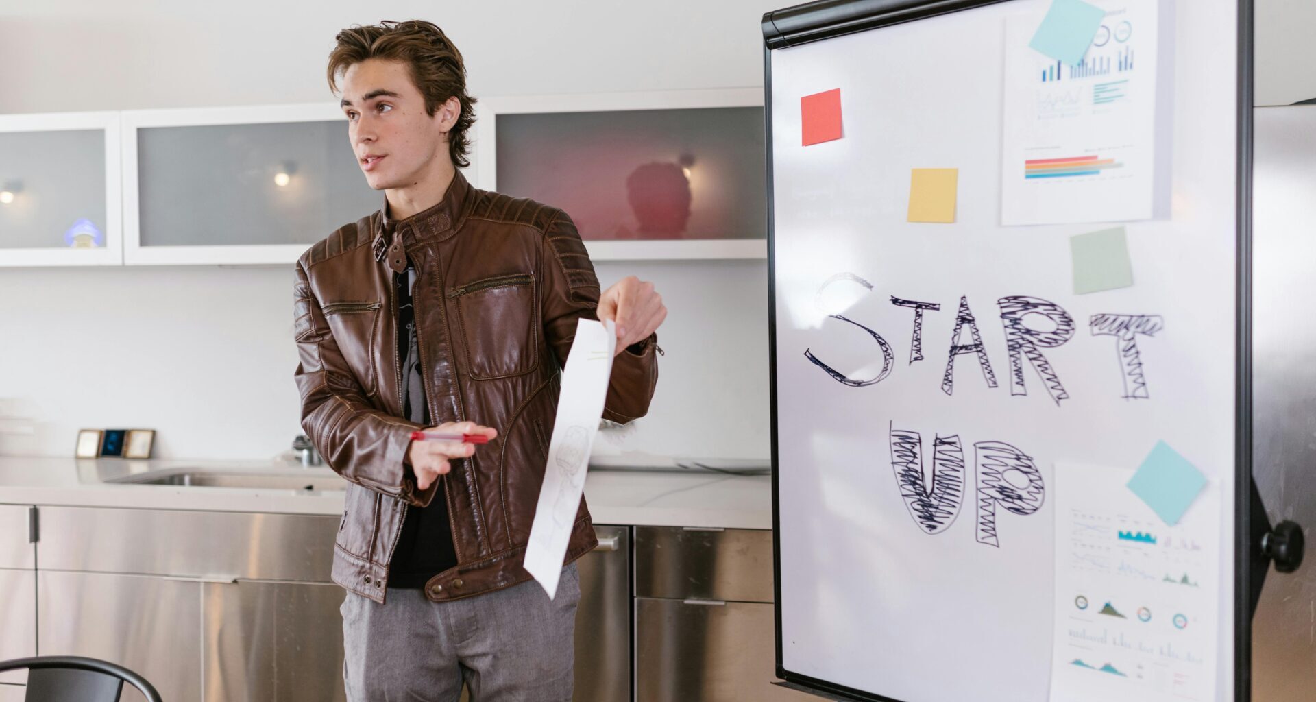 Young man in front of a whiteboard explaining a project