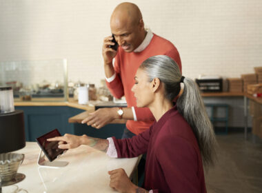 Young woman and man on phone looking at laptop in a promo photo for Verizon Small Business