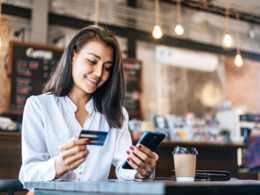 Woman using a mobile phone to pay with purchase with a credit card