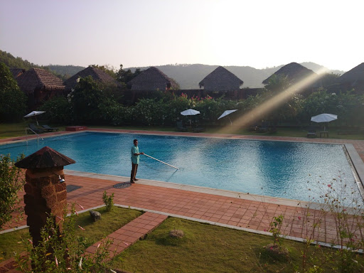 Man cleaning pool with sun on water and long cleaning equipment for swimming pool