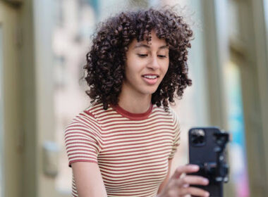 Young woman adjusting a camera phone on a tripod