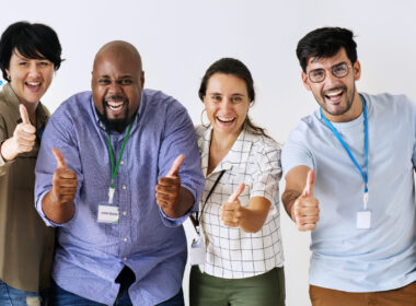 Four employees smiling and showing thumbs up appreciation