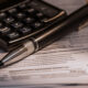 Pen and calculator with tax documents in an image by Image by vecstock on Freepik