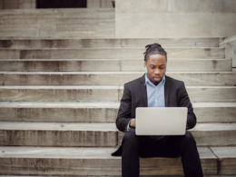 a businessman sitting on court steps using laptop to conduct business