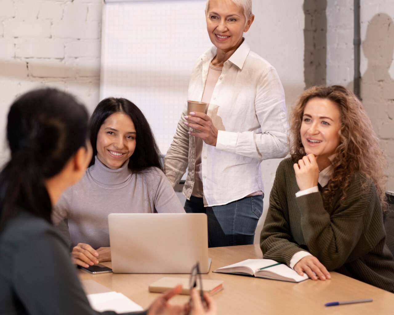 Woman holding coffee and communicating with colleagues in a work setting