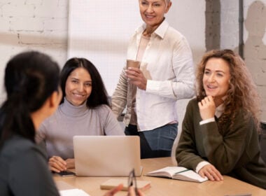 Woman holding coffee and communicating with colleagues in a work setting