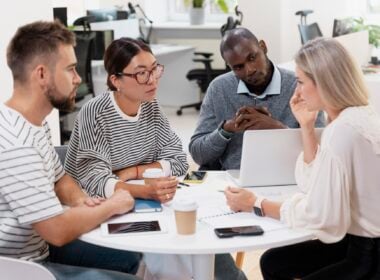 young colleagues having a meeting around a desk and a laptop