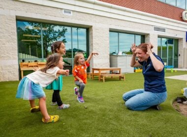 Teacher and children playing outside child care center