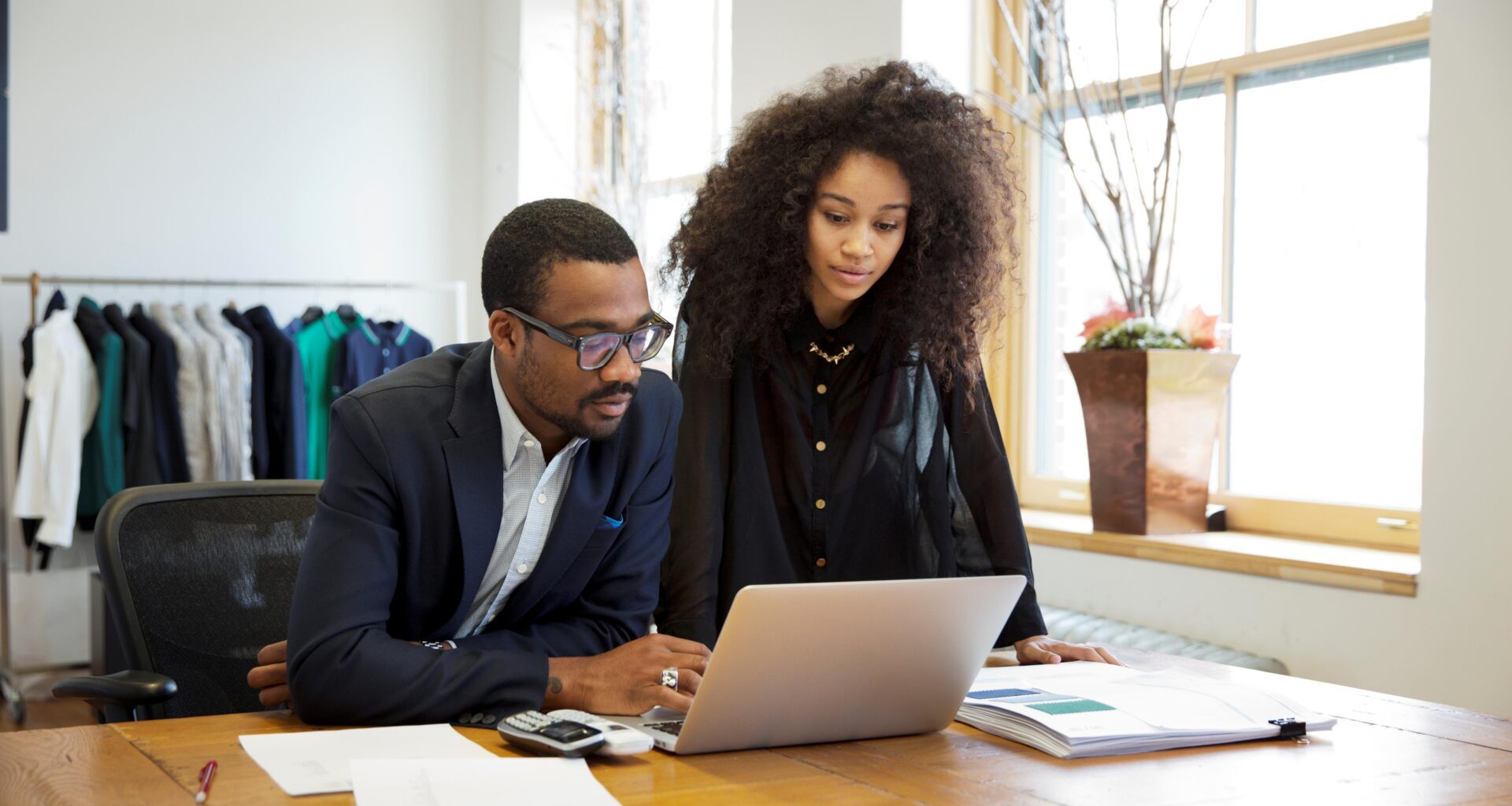 Man and woman looking at a laptop computer discussing small business tactics.