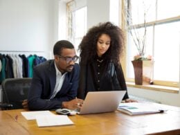 Man and woman looking at a laptop computer discussing small business tactics.