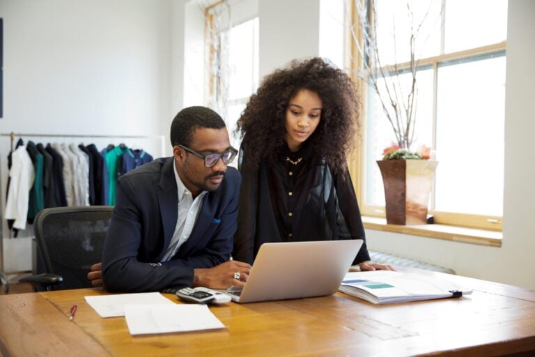 Man and woman looking at a laptop computer discussing small business tactics.