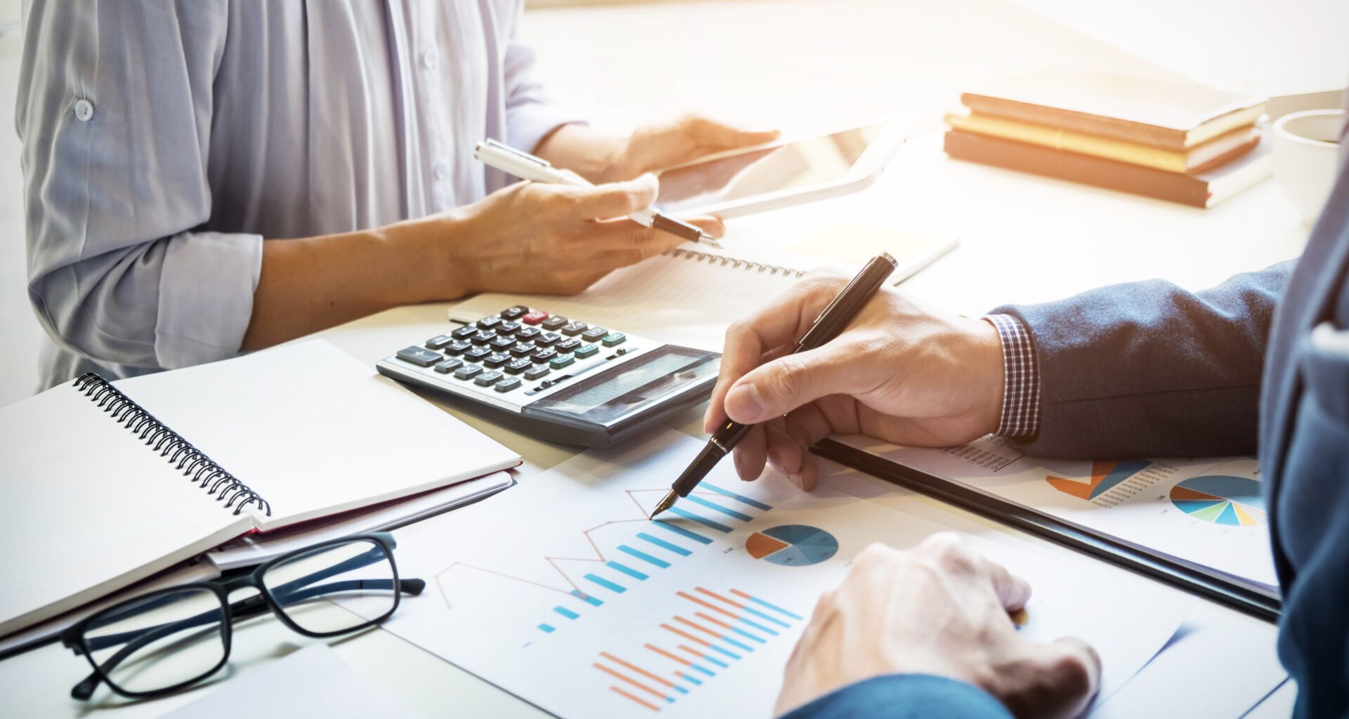 Accountant checking figures with calculator and reports and working with a woman on a project.