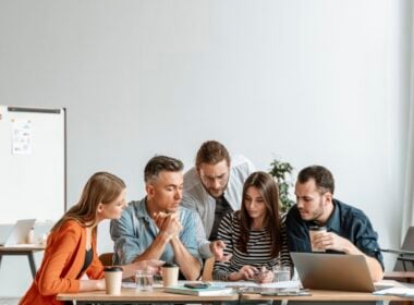 Young office colleagues gathered around a table working on a project together.