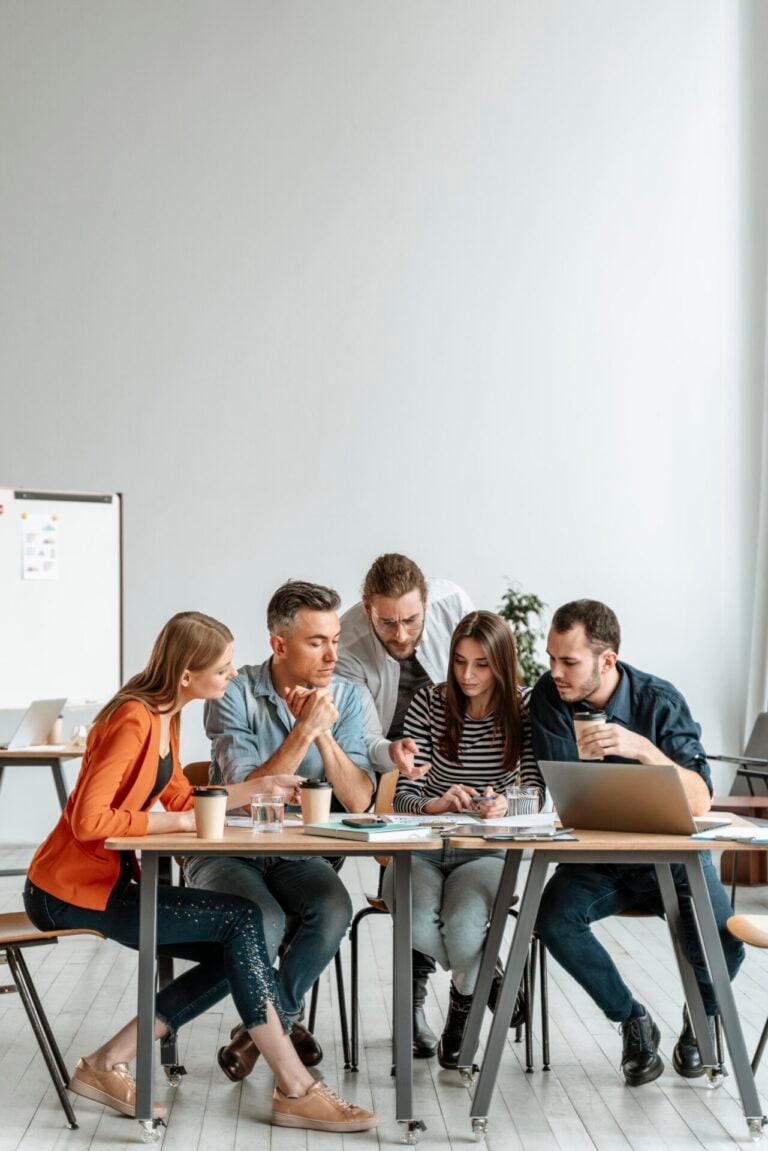 Young office colleagues gathered around a table working on a project together.