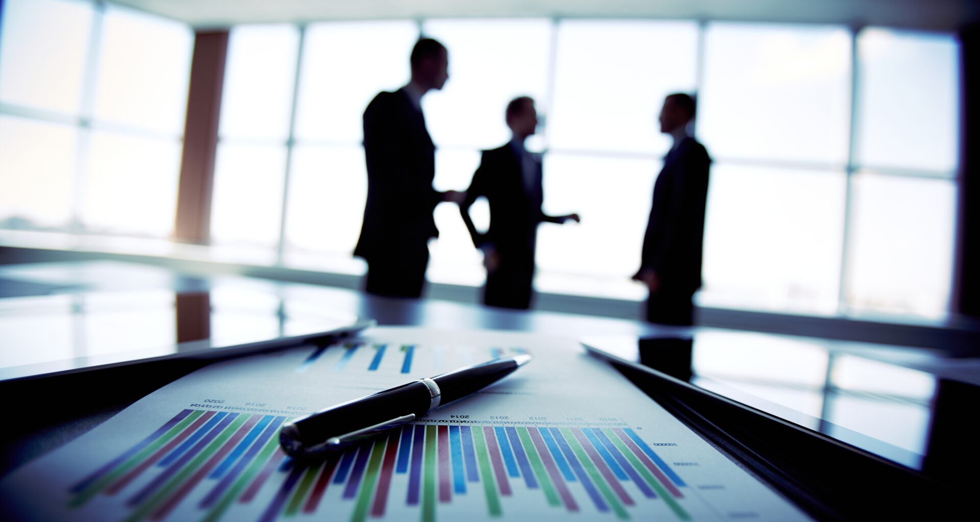 Close-up of a business agreement with business people in shadow in the background